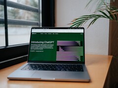 Pencerenin yanındaki masanın üzerinde, ekranında OpenAI ChatGPT web sitesi açık olan bir dizüstü bilgisayar