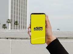Sarı bir ekranda "eSIM" kelimesinin büyük harflerle yazıldığı bir akıllı telefonu tutan bir el.