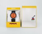 Turuncu kadranlı Seiko 5 Sports x Popeye HDB013 otomatik saat, sınırlı sayıda üretilmiş sarı sunum kutusunun yanında duruyor.