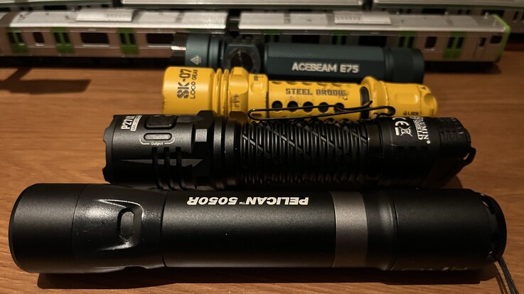 Loop Gear’ın sarı renkli SK-07 modeli, Acebeam E75 (arkada), Nitecore P27i ve Pelican 5050R ile karşılaştırıldığında