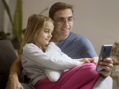 Bir baba ve kızı birlikte bir akıllı telefona bakıyor