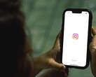 İki eliyle bir akıllı telefon tutan kadın; ekranda Instagram başlangıç ekranı görünüyor