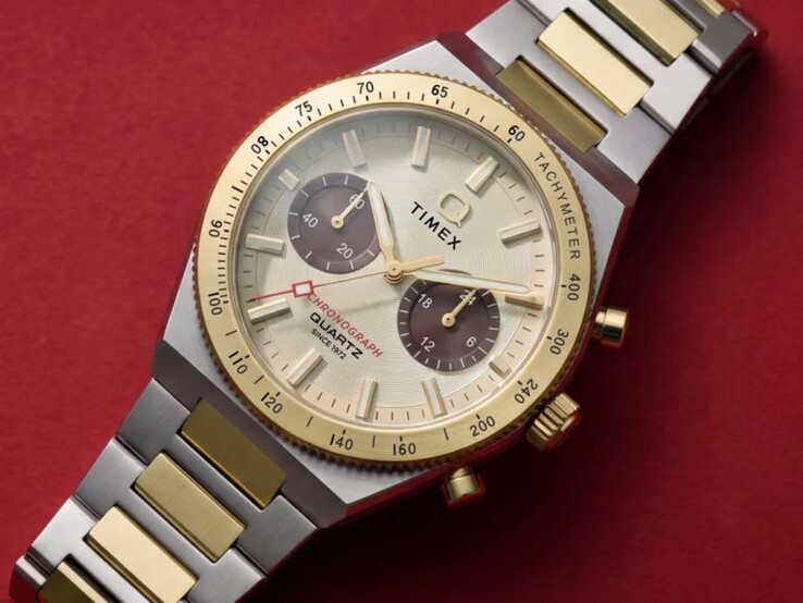 Timex Q Timex Continental Chronograph TW2Y92300 saatinin bileğe takılmış halinin yakın çekimi; altın rengi kadranı, kahverengi alt kadranları, takimetre çerçeve ve iki renkli paslanmaz çelik bileziği gösterilmektedir.