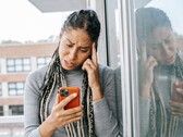 Bir kadın ciddi bir ifadeyle akıllı telefonuna bakıyor